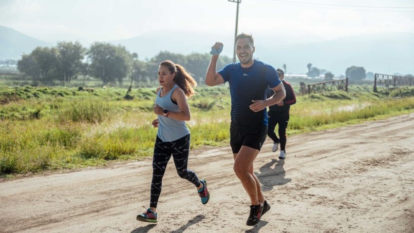 A group of runners enjoys a vibrant morning jog on a rural dirt road.